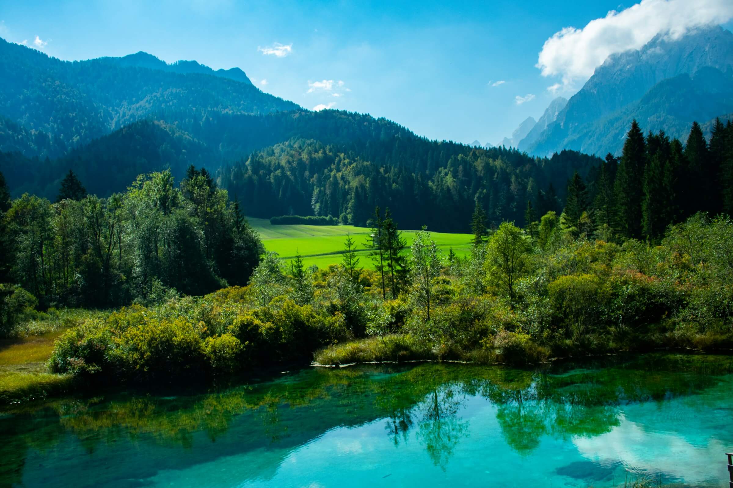Green valley with mountains, forest and a blue-green lake