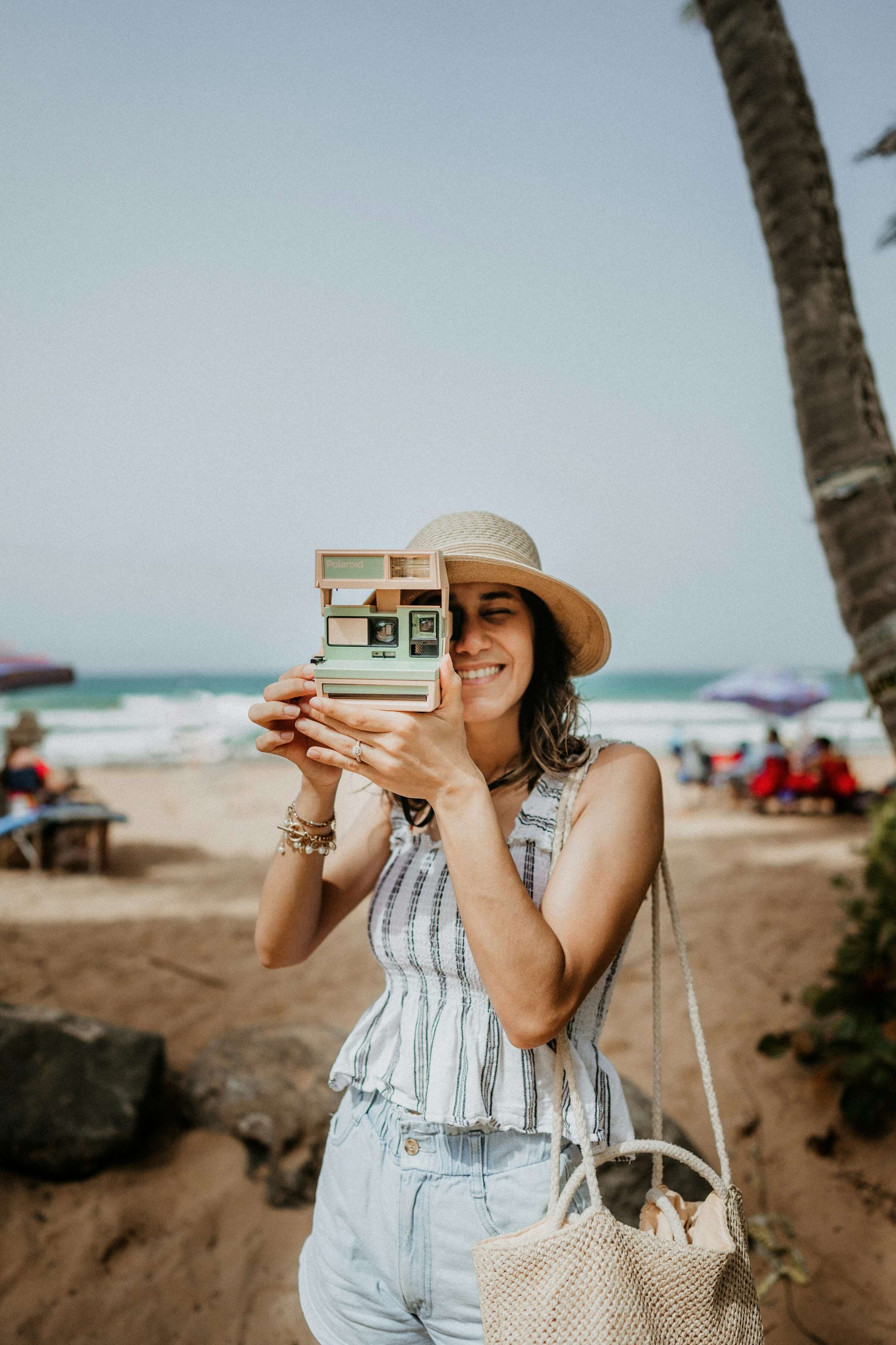 A traveller photographing with a Polaroid camera on the beach